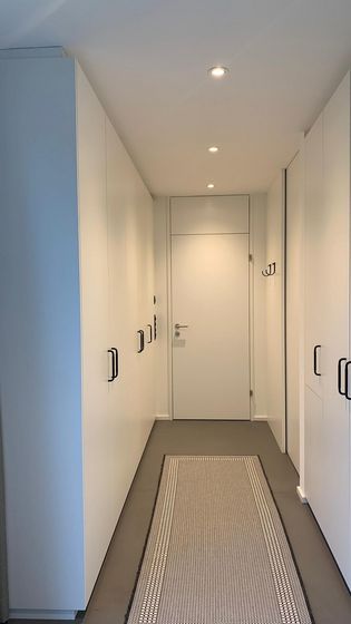 Moderner Flur mit Einbauschränken und Teppichläufer in minimalistischem Design.