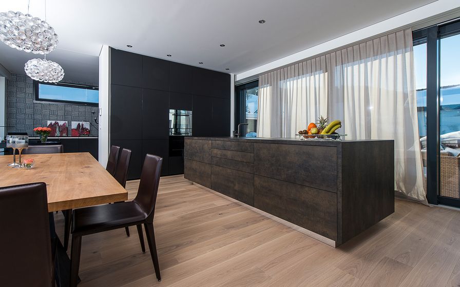 Moderne Küche mit Holzfussboden und dunklen Schränken.