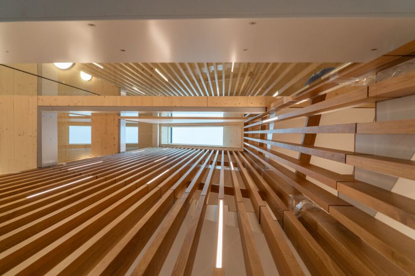 Innenperspektive eines Raumes mit holzverkleideten Wänden und Deckenstreben, die ein modernes Design betonen.