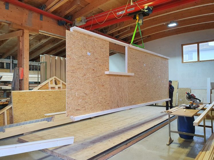 Holzplatte wird in einer Werkstatt von einem Kran angehoben.