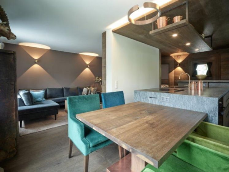 Modern eingerichteter Wohnraum mit Holztisch und farbigen Stühlen.