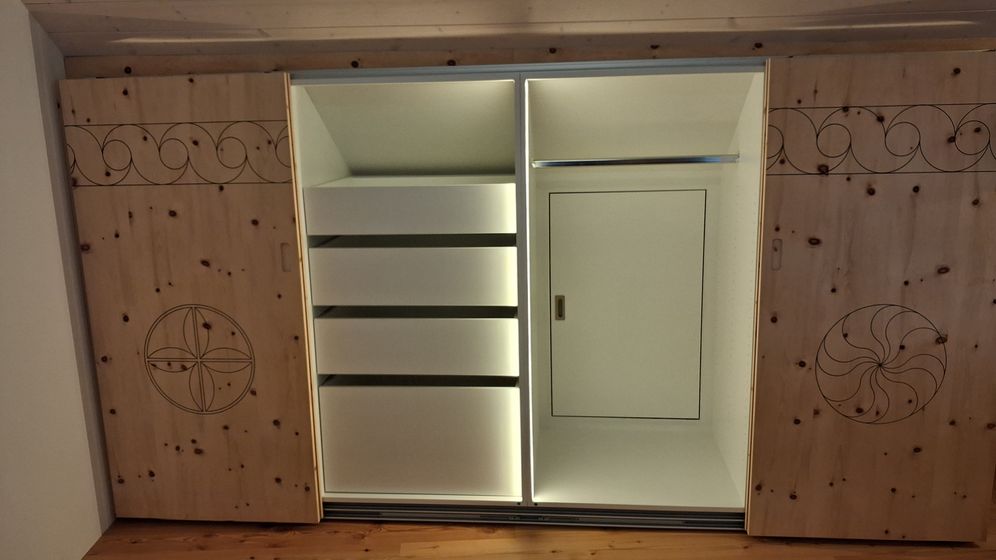 Eingebauter Schrank mit verzierten Holztüren und moderner Beleuchtung.