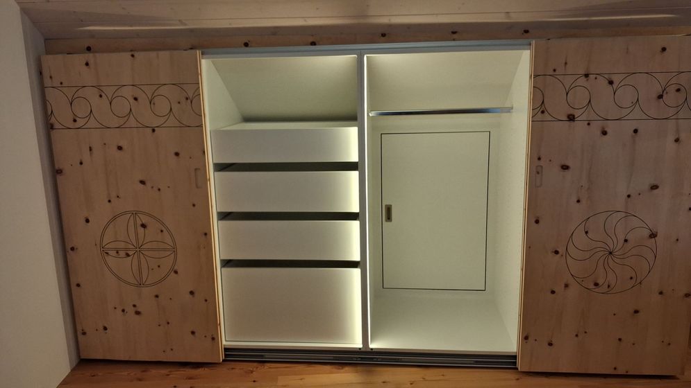 Eingebauter Schrank mit verzierten Holztüren und moderner Beleuchtung.