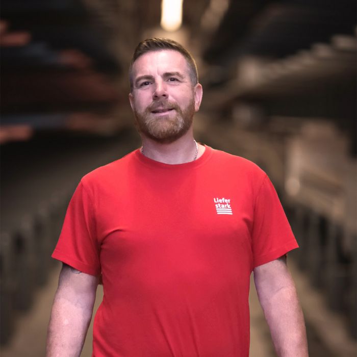 Mann im roten T-Shirt von Stark AG in Holzlager.