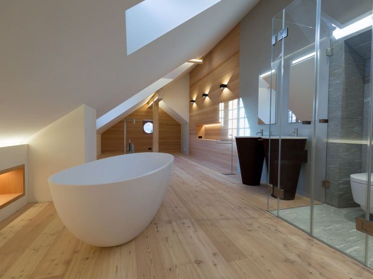 Modernes Badezimmer mit freistehender Badewanne und Holzboden in Dachgeschoss.