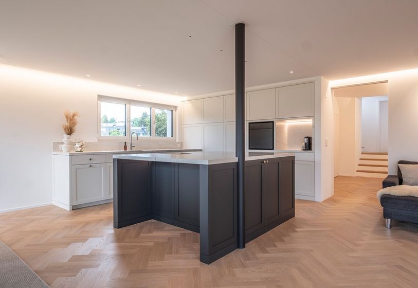 Moderne Küche mit Kochinsel, hellen Schränken und breiten Fenstern.