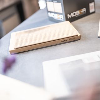 Holzwerkstoffmuster auf Tisch mit Verpackung im Hintergrund.