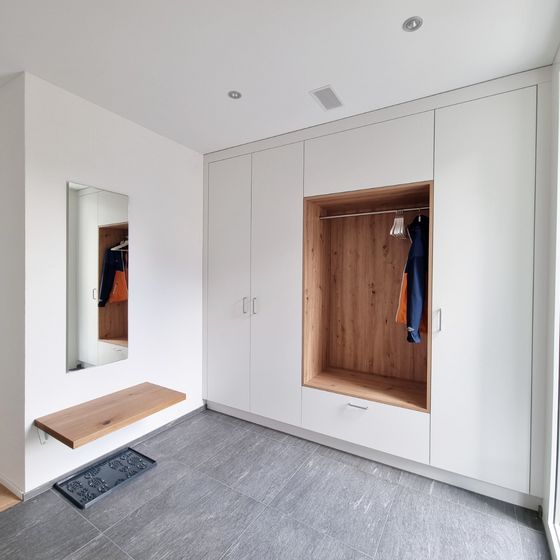 Moderner Einbauschrank aus Holz mit offenen Fächern und seitlichem Spiegel.