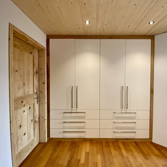 Moderner Einbauschrank aus Holz mit passender Tür in einem Raum mit Holzdecke und Holzboden.
