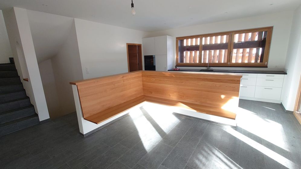 Moderne Küche mit Holzverkleidung und grossem Fenster.