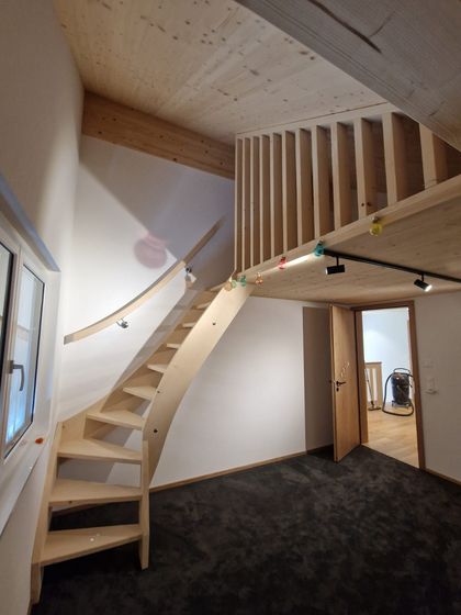 Moderne Holztreppe in einem Innenraum mit schwarzem Teppichboden.