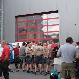 Gruppe von Menschen bei einer Veranstaltung vor einem industriellen Gebäude.