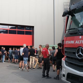 Gruppe von Menschen vor der Lagerhalle von Stark Altstätten und einem LKW.