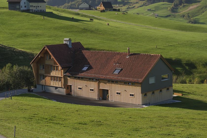 Schweizer Bauernhof im grünen Tal bei Sonnenschein.