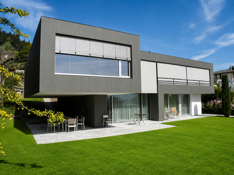 Modernes Haus mit grosser Glasfassade und gepflegtem Rasen.