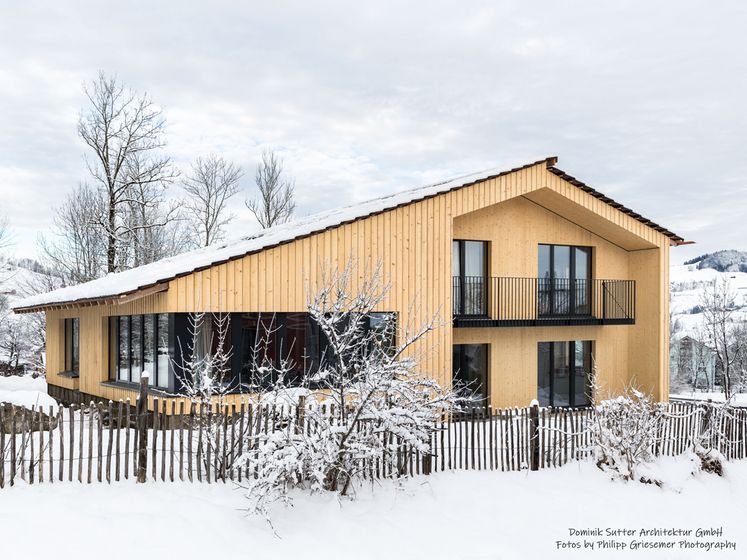 Modernes Holzhaus in verschneiter Landschaft.