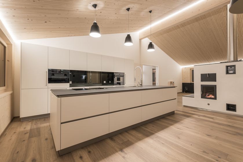 Moderne Küche mit Holzdecke und stilvolle Beleuchtung in einem offenen Wohnraum.