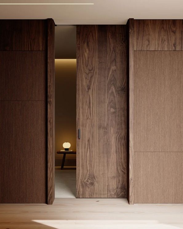 Elegante Holztür öffnet sich, um minimalistisches Interieur mit Tisch und Lampe zu enthüllen.