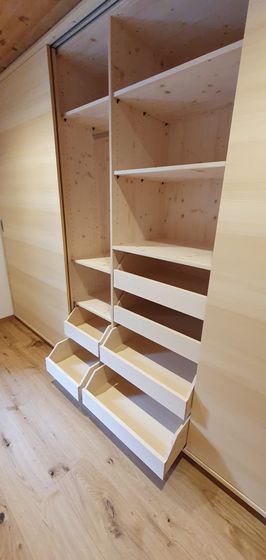 Offener Holzschrank mit Regalen und Schubladen in einem modernen Innenraum.